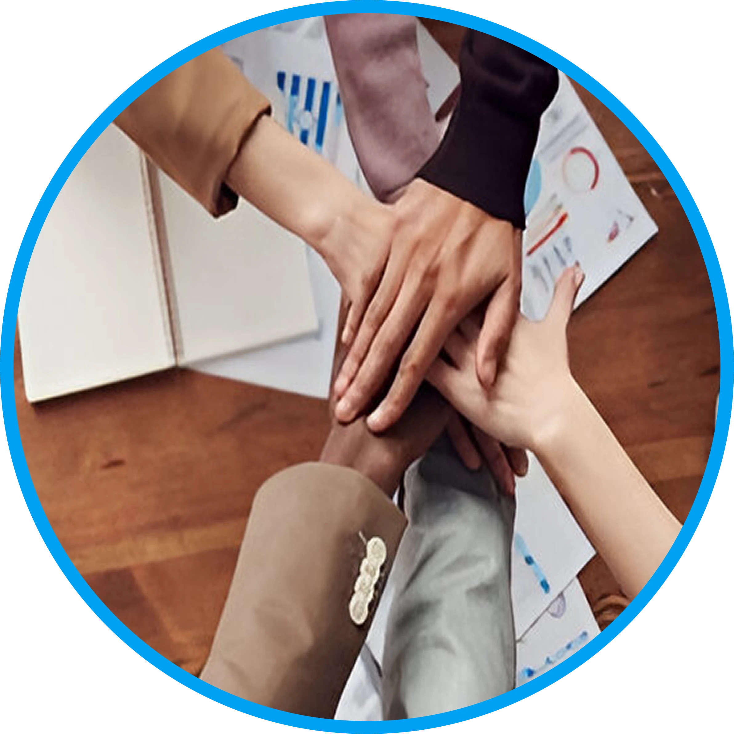 Five hands of diverse individuals coming together over a table with documents.